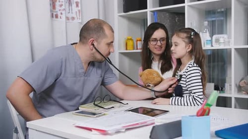 Médico masculino en el consultorio lleva a los pacientes. El médico de familia examina a una niña que vino su madre