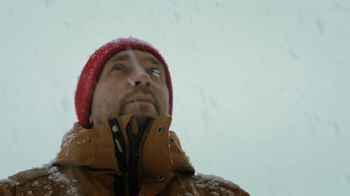 Man in Red Hat Watching Snow Falling