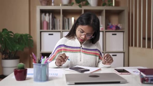 Focused Black Girl with Eyeglasses Uses Calculator and Writes Notes Studying for the University