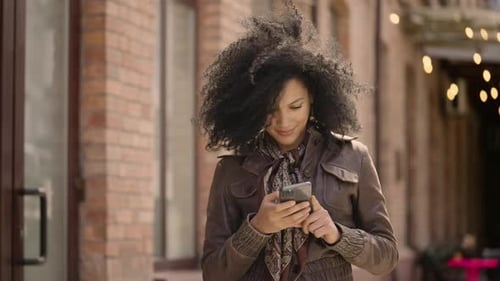 Woman Uses Smartphone Outside Brick Building