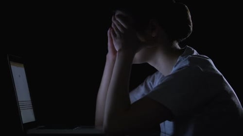 Distressed Woman at Computer in Dark Room