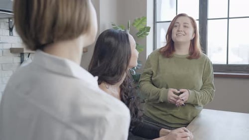 Charmante femme rousse de grande taille écoutant un ami parler devant et souriant