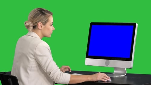 Young woman working in office sitting at desk, looking