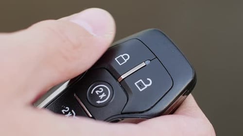 Mann verriegelt und entriegelt das Auto mit Schlüsselanhänger-Nahaufnahme auf hellgrauem Hintergrund