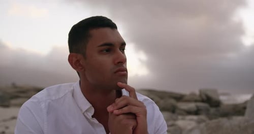 Man with hands on chin sitting on the beach