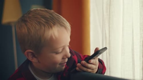 Child Talking on Cell Phone Near Window
