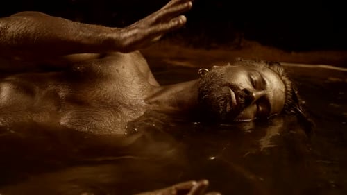 Un ritual chamánico en el agua se mueve en movimiento en una danza con pintura dorada en la piel