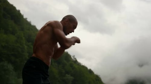 Shirtless Man Boxing Outdoors in Misty Mountains
