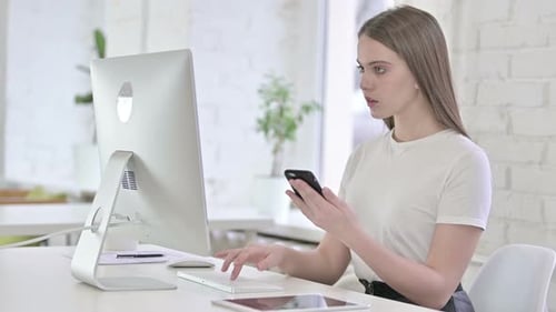 Jolie jeune femme utilisant un smartphone et travaillant sur un bureau