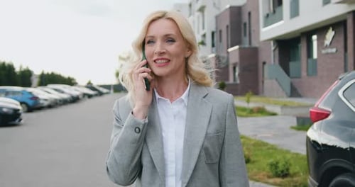 Businesswoman Walking on Street in City and Speaking on Mobile Phone Onthe go to Office Outdoors.