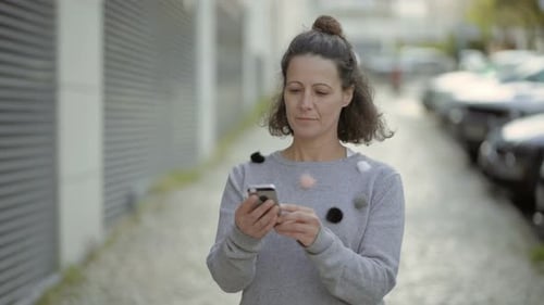 Woman Using Smartphone While Walking on City Sidewalk