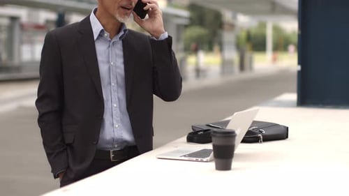 Businessman standing at train station talking on the phone