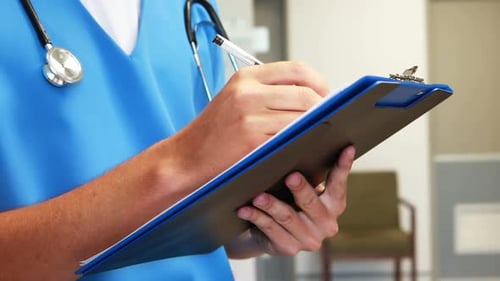 Healthcare Worker Writes on Clipboard in Hospital Setting