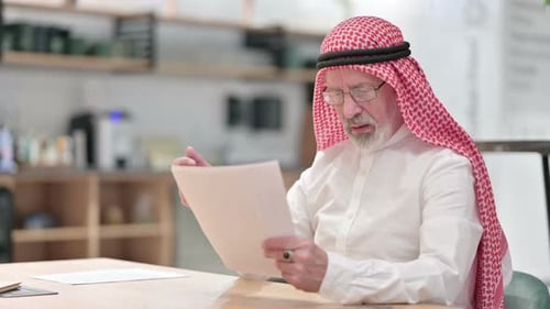 Frustrated Man Reviews Documents at Office Desk