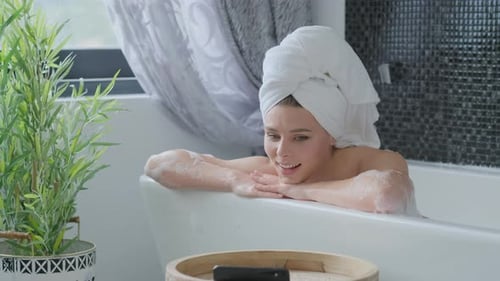 Woman Relaxing in a Soapy Bathtub with Cellphone