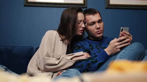 Couple Relaxing Indoors Looking at Smartphone Together