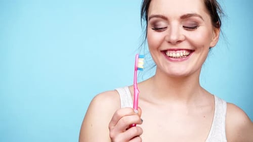 Woman Smiles Holding Pink Toothbrush