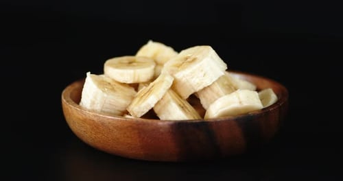 Rotating Bowl of Sliced Bananas on Black