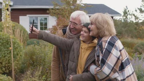 Grandparents and Teen Smiling at Phone Outdoors