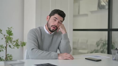 Joven soñoliento tomando una siesta mientras está sentado en la oficina