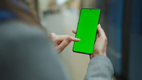 Woman at the Street Using Smartphone with Green Mockup Screen in Vertical Mode