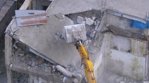 Excavator Demolishing Damaged Building in Urban Environment