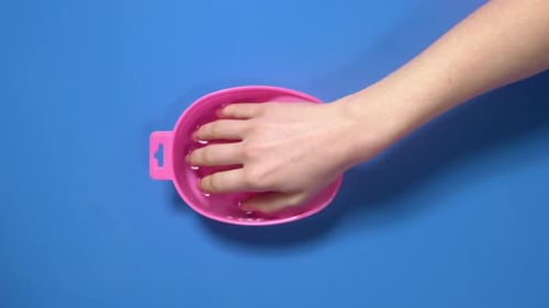 Mulher coloca a mão para o banho de unhas antes da manicure, os preparativos para a manicure cortada, no