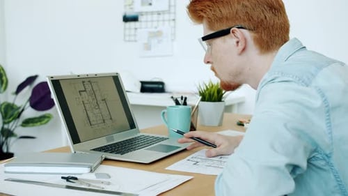 Ambitious Architect Checking Construction Plan Looking at Laptop Screen Working in Office Alone