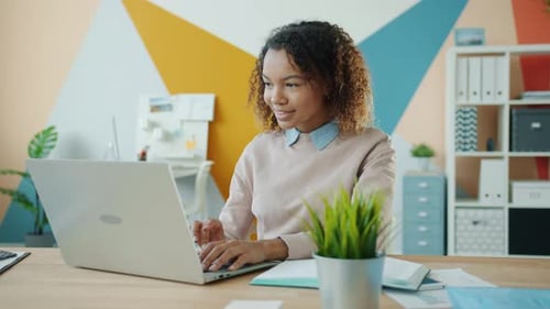 Slow Motion of Mixed Race Lady Working with Laptop in Office Then Writing Info in Notebook