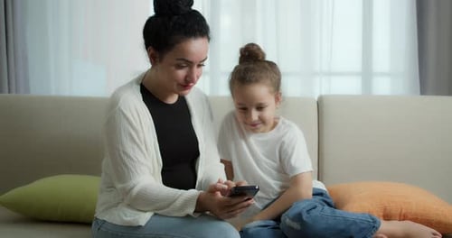 Woman and Child Using Smart Phone on Couch