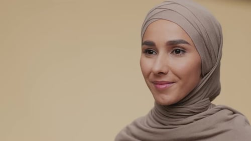 Retrato de semiperfil de una joven musulmana pacífica con el hijab tradicional mirando a un lado y en voz baja