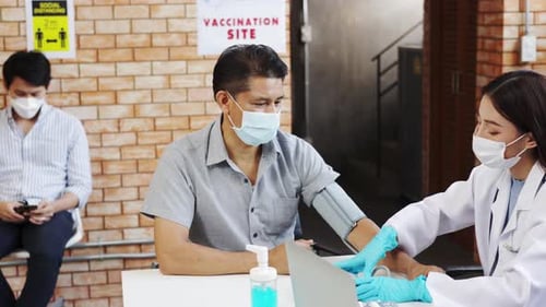 Health Worker Checks Patient's Blood Pressure at Vaccination Site