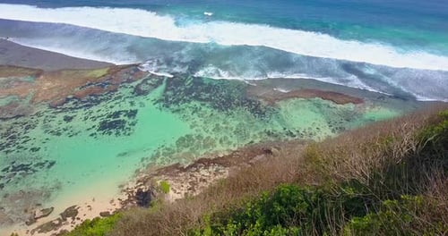 Drohnenaufnahme eines Korallenriffs und Wellen am Strand