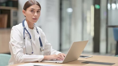 Friendly Female Doctor with Laptop Smiling in Office