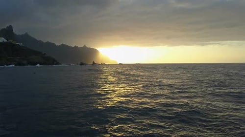Flight Above Ocean Waves Facing Beautiful Sunset and Mountains on Horizon. Aerial Drone Shot of