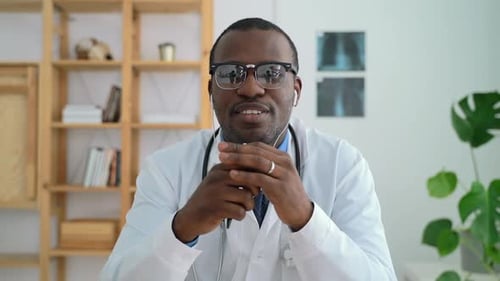 African American Man Doctor Talking During Online Meeting at Table in Clinic Spbas