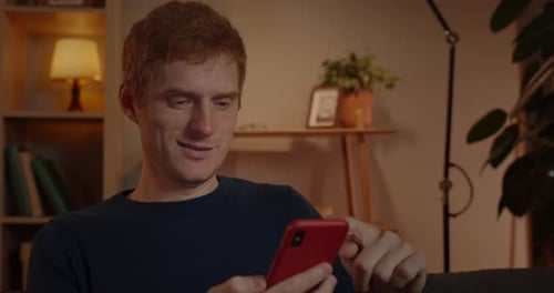 Close Up View of Cheerful Man Using Smartphone While Sitting on Couch at Home