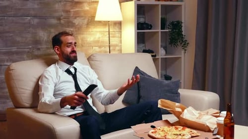 Man Eats Pizza and Drinks Beer on Couch