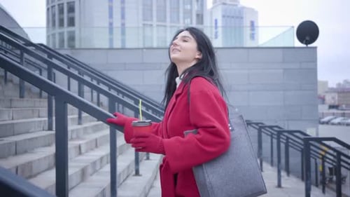 Side View of Positive Brunette Caucasian Girl Walking Up the Stairs in City. Young Beautiful Woman