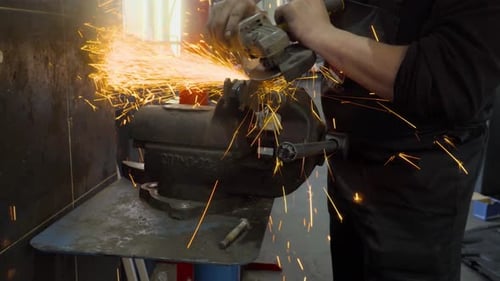 Primer plano de un trabajador con una amoladora corta metal en un taller