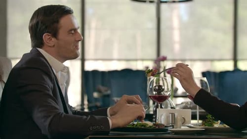 Beautiful Woman Feeding Man at Dinner. Couple in Love Dining in Restaurant