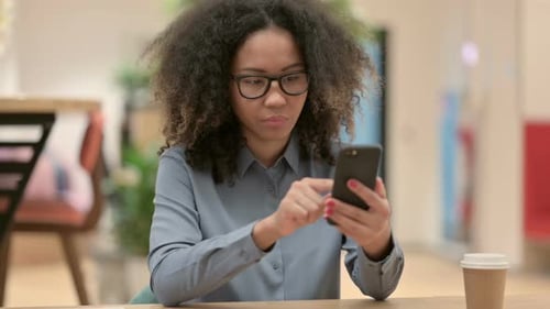Woman Using Smartphone at Table Indoors