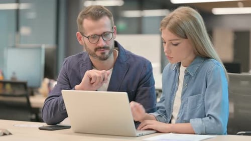Geschäftsmann und Geschäftsfrau diskutieren im Büro am Laptop