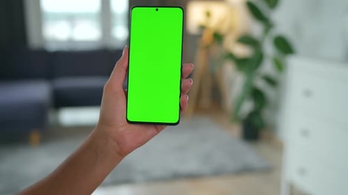 Woman at Home Using Smartphone with Green Mockup Screen in Vertical Mode