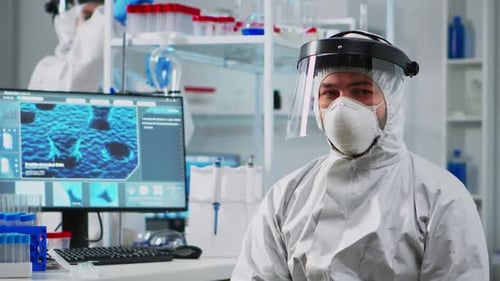 Scientist in Protective Suit Sitting in Laboratory