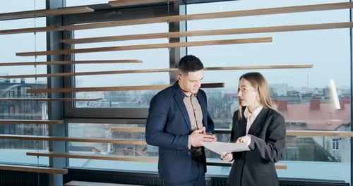 Man and a Woman Discussing Work in the Brightly Lit Modern Office. Concerned Male and Female Working