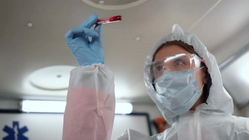 Medical Professional Examines Blood Sample in Ambulance