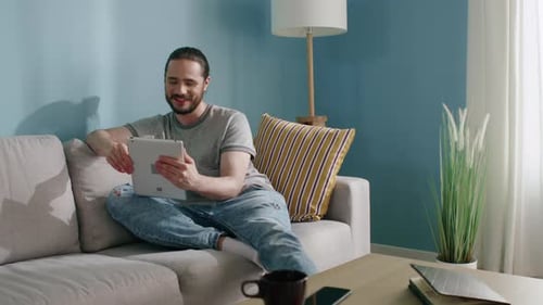 Man Relaxing on Couch Using Tablet Indoors