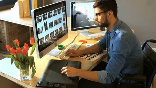Man in Wheelchair Works at Computer in Office