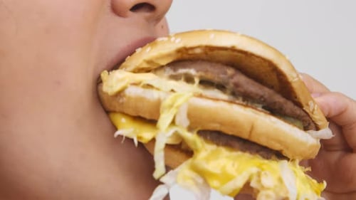 Woman Eats Large Hamburger in Close Up Shot